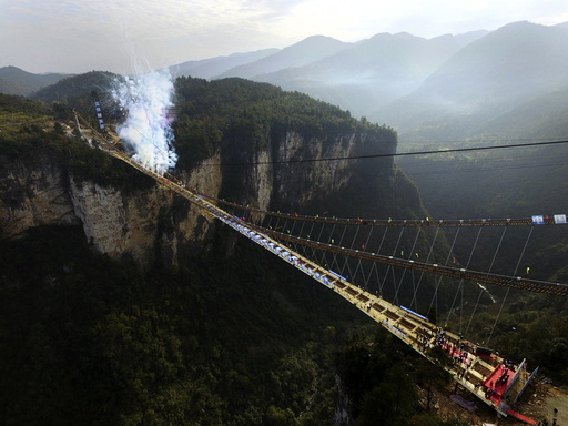 Fireworks go off to celebrate completion of construction of steel box girder on glass bridge as it suspends over canyon in Zhangjiajie National Park