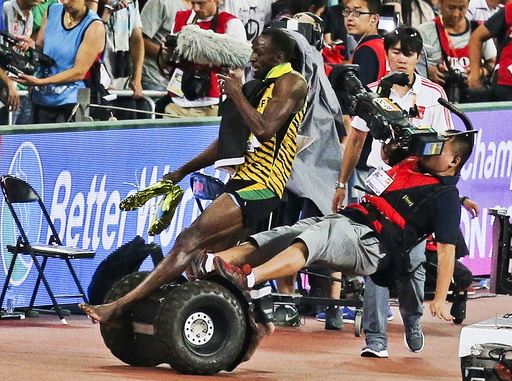 Usain Bolt of Jamaica is hit by a cameraman on a Segway as he celebrates winning the men's 200m final at the 15th IAAF World Championships in Beijing, China